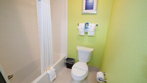 Ein Badezimmer mit Toilette, einer Badewanne, einer Duschvorhang, einem Mülleimer und einem Handtuchhalter mit Handtüchern.