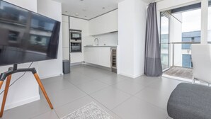 A modern apartment with a kitchen, a balcony with a view, and a flat-screen TV. - Pet-friendly With Balcony and Shared Garden (London)