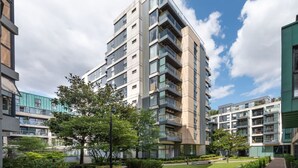 A modern high-rise residential building with multiple balconies, surrounded by well-maintained greenery and a clear sky. - Pet-friendly With Balcony and Shared Garden (London)