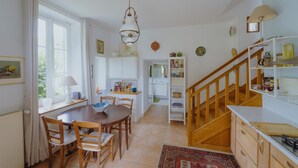 A spacious kitchen with a dining area, wooden staircase, and a view of the garden. - La Maison de Yette - CHEILLY-LES-MARANGES (CHEILLY-LES-MARANGES)
