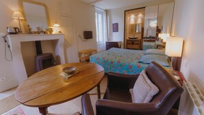 A cozy hotel room with a bed, a wooden table, a chair, a desk, and a mirror. - La Maison de Yette - CHEILLY-LES-MARANGES (CHEILLY-LES-MARANGES)