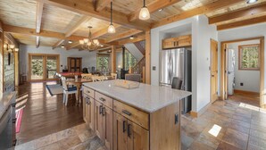 A spacious kitchen with wooden cabinets, a granite countertop, and a stainless steel refrigerator. - Pet-Friendly Creek Cabin on 8 Acres - Billiards, Borders Natl Forest (Alma)