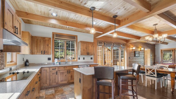 A spacious kitchen with wooden cabinets, a large island, and a dining area with a table and chairs. - Pet-Friendly Creek Cabin on 8 Acres - Billiards, Borders Natl Forest (Alma)