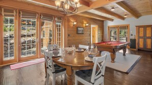 A spacious dining area with a wooden table, white chairs, and a pool table. - Pet-Friendly Creek Cabin on 8 Acres - Billiards, Borders Natl Forest (Alma)