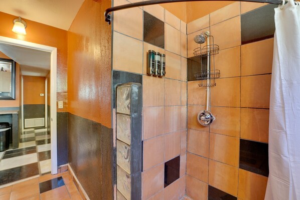 A shower with a curved door, a glass partition, and a showerhead.