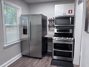 Cocina compacta con refrigerador de acero inoxidable, microondas y horno.