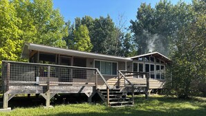 A two-story house with a deck and a staircase leading to the upper level. - Rustic Cabin Getaway Near Kenora (Kenora)