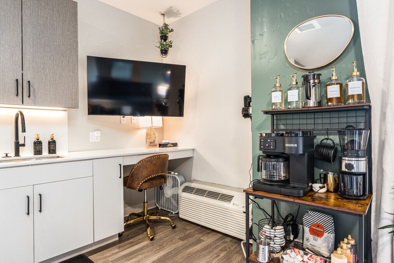 A compact kitchenette with a modern design, including a built-in TV, a coffee maker, and a small seating area.