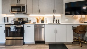 A modern kitchen with stainless steel appliances, white cabinetry, and a built-in microwave.