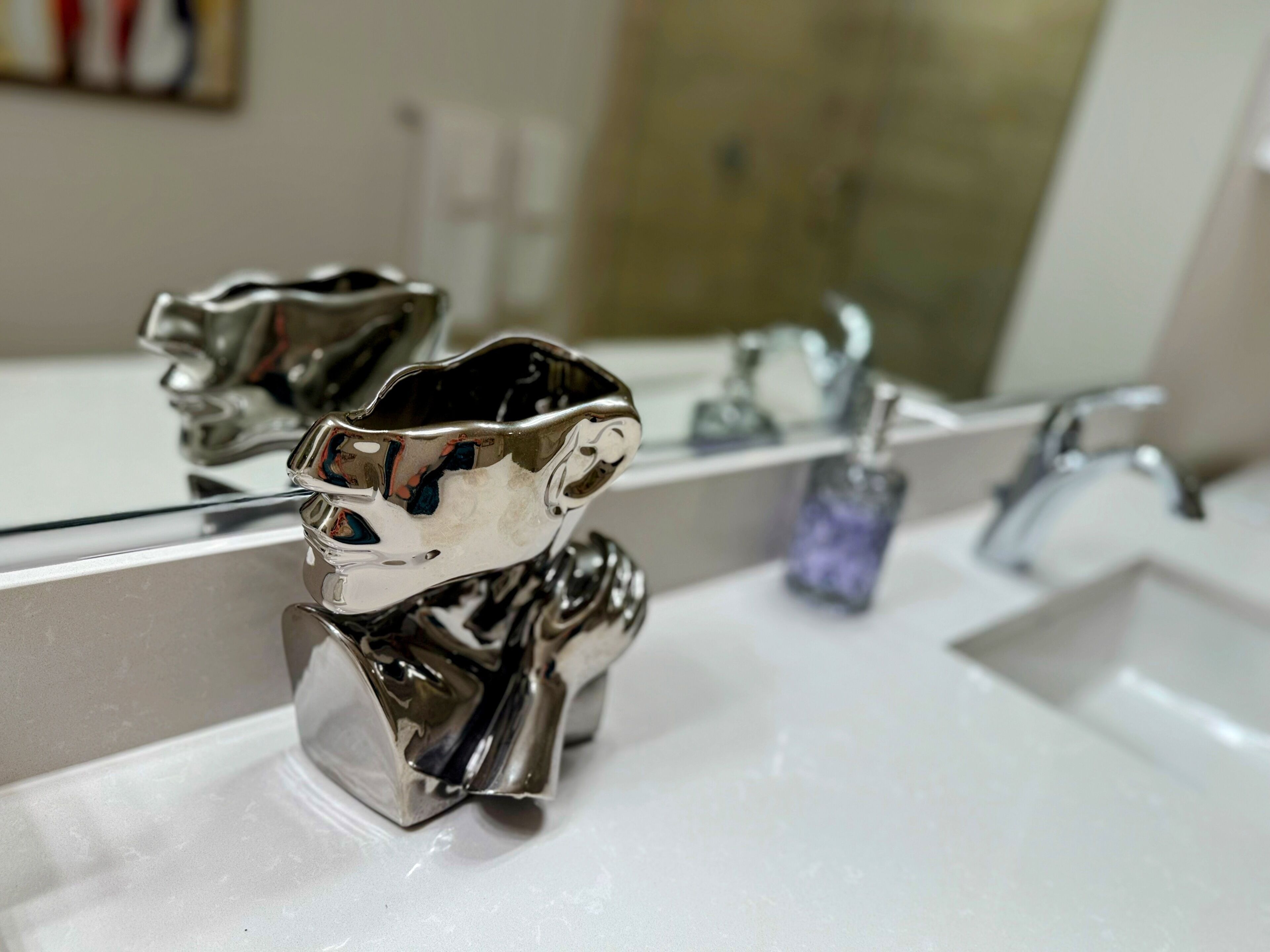 Un baño con un lavamanos moderno y un grifo metálico decorativo.