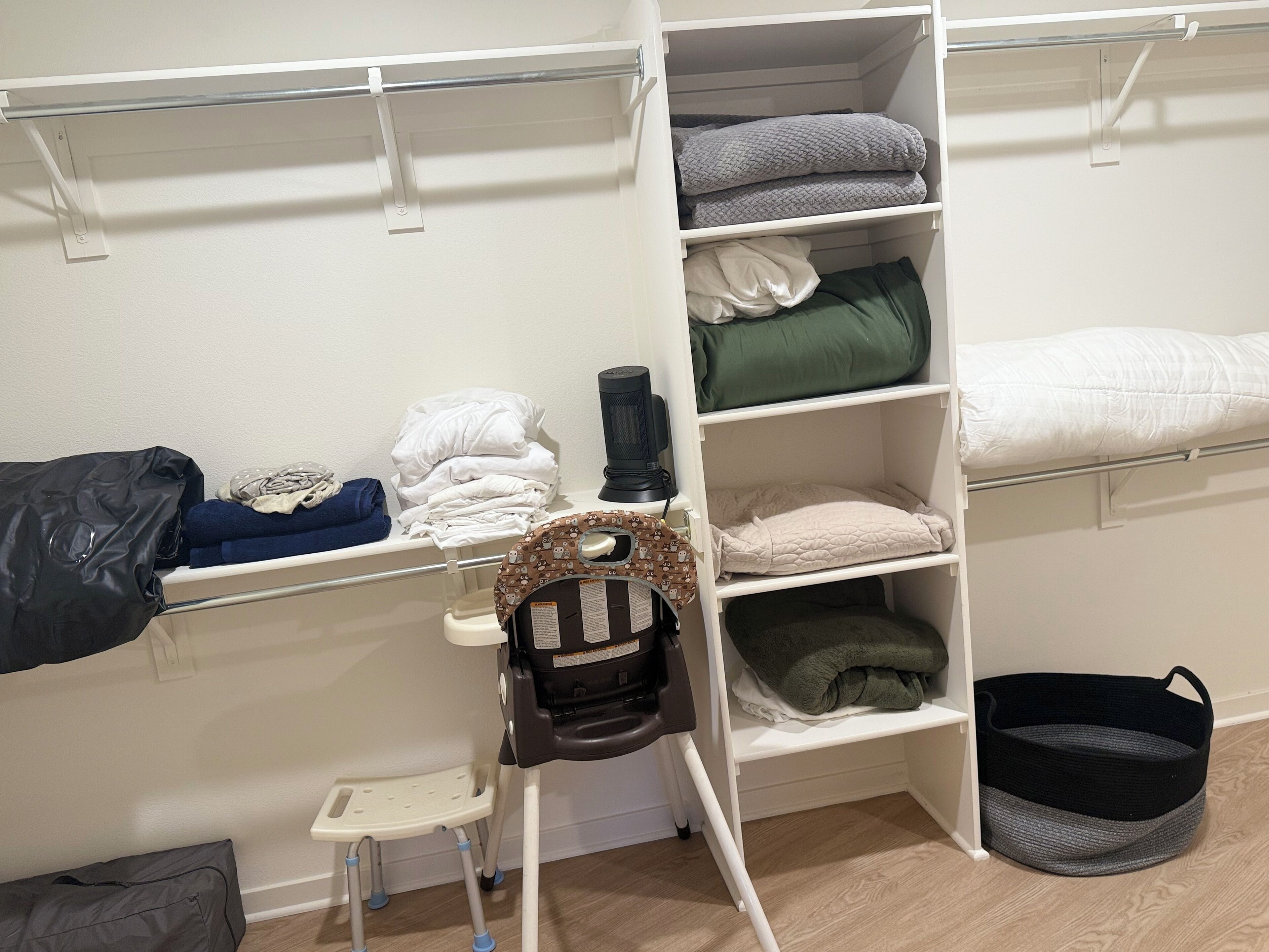 A bedroom with a bunk bed, a small chair, and a storage unit with shelves.