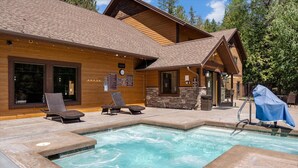 Un chalet en bois doté d’une piscine, de chaises longues et d’un espace barbecue couvert.