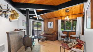 Un vaste espace de vie doté d’un plafond en bois, d’une cheminée, d’un canapé et d’une table à manger.