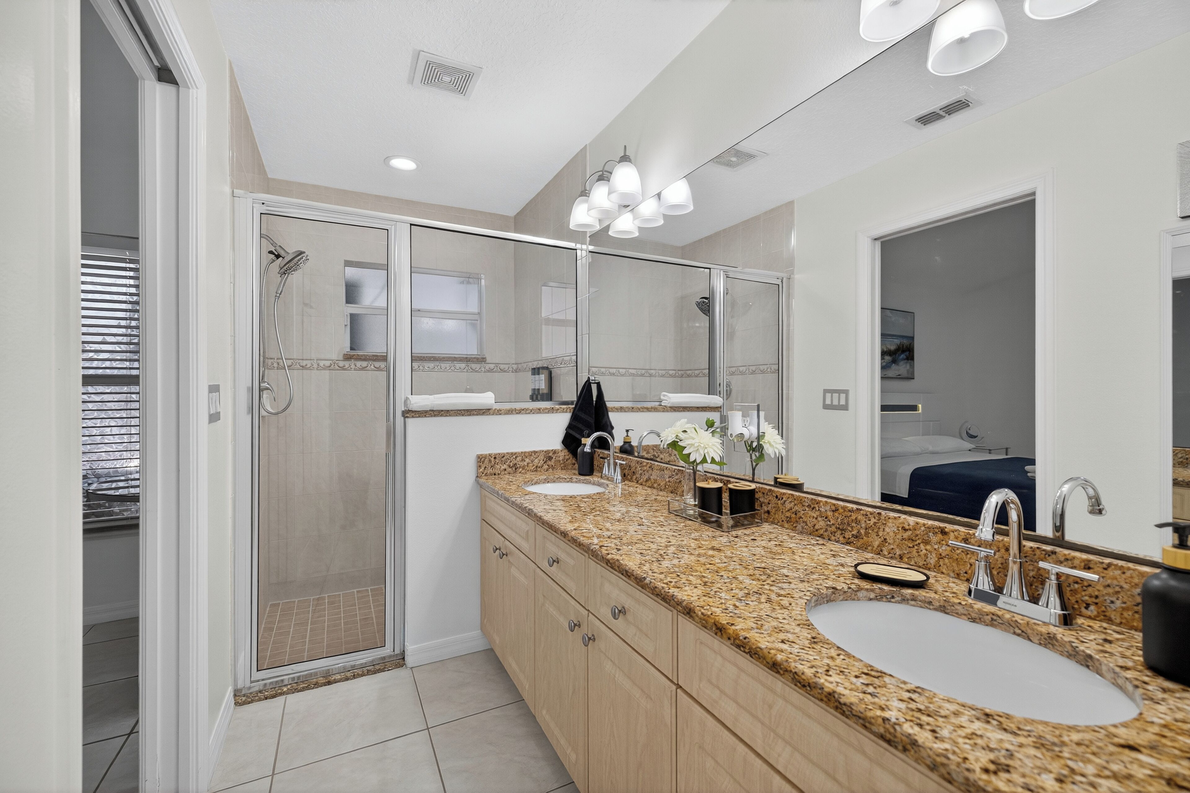 A modern bathroom with a glass-enclosed shower, a double sink vanity, and a large mirror.