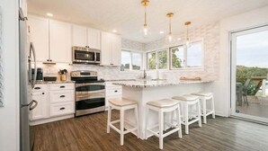 A modern kitchen with white cabinets, stainless steel appliances, and a large island with bar stools.