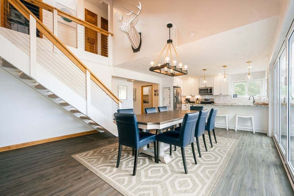 A spacious kitchen with modern appliances, a dining area with a large table and chairs, and a staircase leading to an upper level.