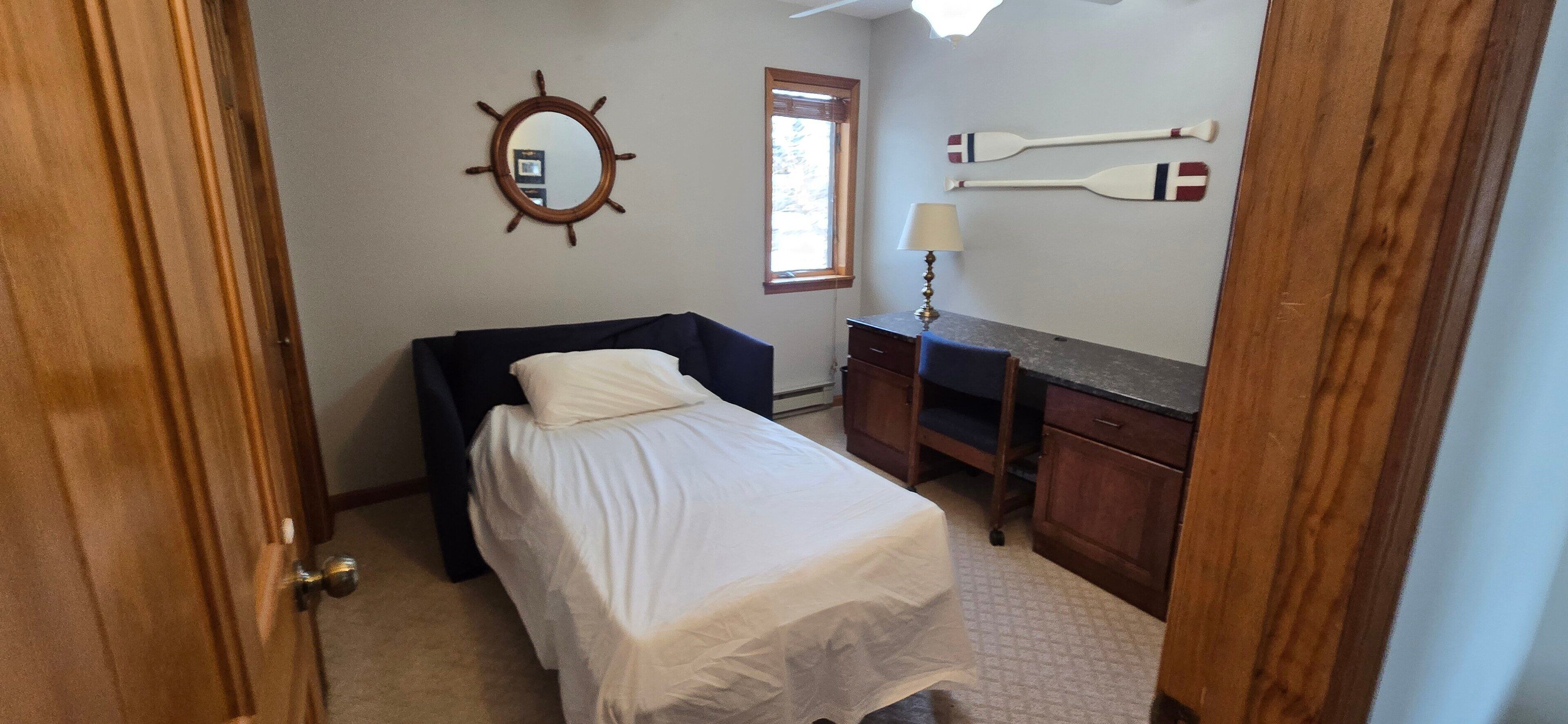 Une chambre à coucher comprenant un lit, une commode, un miroir et deux panneaux fixés au mur.