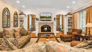 A spacious living room with a fireplace, comfortable seating, and bookshelves.