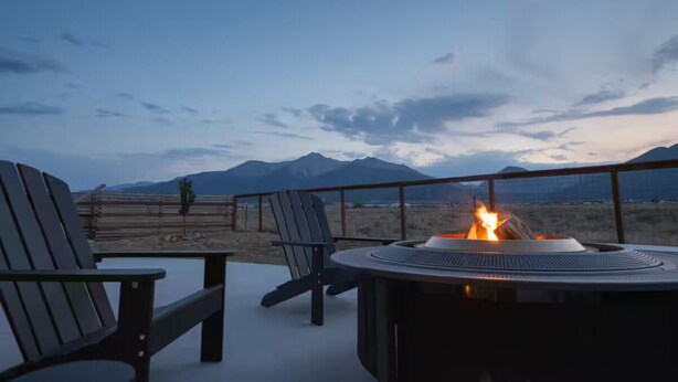Une terrasse avec deux fauteuils Adirondack, un foyer circulaire et une vue sur les montagnes.