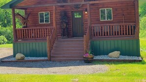 Une cabane en bois avec une véranda, des marches et une porte.