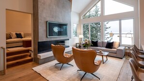A spacious living room with a fireplace, a sofa, two armchairs, and a coffee table. - Northern Lights 32 | Ski-in/out Luxury Townhome, Hot Tub, (Whistler)