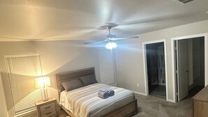 Ein Schlafzimmer mit Bett, Nachttisch und Deckenventilator.
