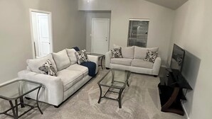 Ein Wohnzimmer mit zwei weißen Sofas, einem Glastisch und einem Deckenventilator.