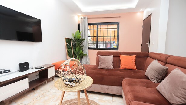 A living room with a sofa, TV, and a plant. - Yalie Home and Co (Rivieria 3 bonoumin)