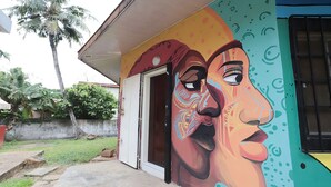 Un edificio con un murale colorato, una porta e un vialetto in cemento.