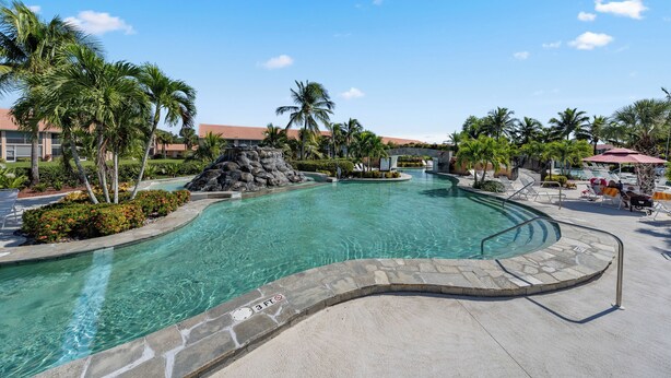 A swimming pool with a stone border, palm trees, and lounge chairs. - Charming Three Bedroom Villa in Beautiful Naples (Naples)