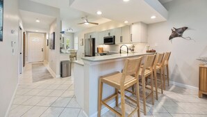 A modern kitchen with a central island, bar stools, and a ceiling fan. - Charming Three Bedroom Villa in Beautiful Naples (Naples)