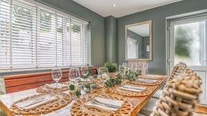 Una mesa de comedor dispuesta con servilletas blancas, cristalería y un mantel tejido.
