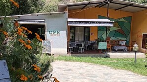 A restaurant with outdoor seating, a sign reading "Café por el Habla Bistro," and a mural on the wall. - CPHHOSTAL (Villa Restrepo)