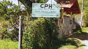 A sign for a rural guesthouse with a rustic wooden structure and lush greenery in the background. - CPHHOSTAL (Villa Restrepo)