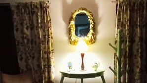 A room with a small table, a chair, a lamp, and a mirror with a gold frame. - CPHHOSTAL (Villa Restrepo)