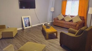 Una sala de estar con sofá, sillones, una mesa de centro, televisor y ventilador de techo.
