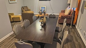 Un salón de conferencias con una mesa larga, seis sillas, un televisor y un sofá al fondo.
