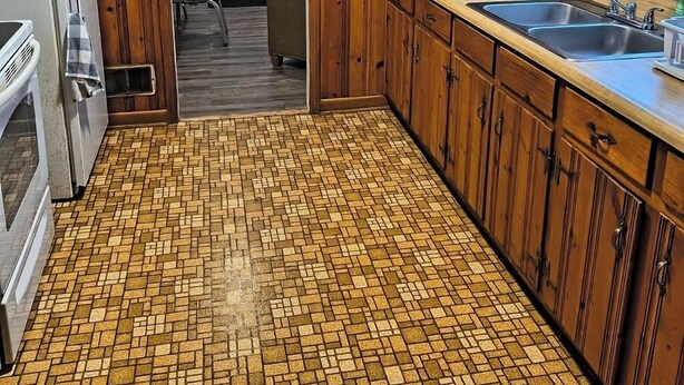 Una cocina con paneles de madera, piso de baldosas y un refrigerador.