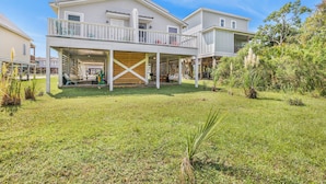 A two-story house with a covered porch and a fenced backyard. - Full Duplex -Steps to Beach, Dining & Shops, 6 Sunny Balconies, Cozy Firepit! (Gulf Shores)