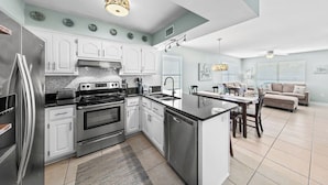 A modern kitchen with white cabinets, stainless steel appliances, and a central island. - Full Duplex -Steps to Beach, Dining & Shops, 6 Sunny Balconies, Cozy Firepit! (Gulf Shores)