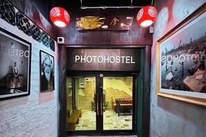 A hotel entrance with a sign reading 'PHOTOHOSTEL' and framed pictures on the walls. - Photohostel (Bangkok)