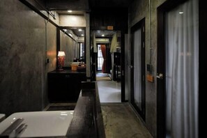 A narrow hallway with a bench, a table with cutlery, and a lamp. - Photohostel (Bangkok)