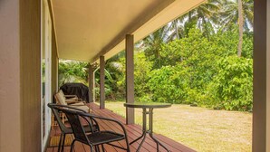Un espacio al aire libre cubierto con una terraza de madera, una mesa y dos sillas.
