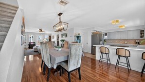 A spacious kitchen with a dining area, wooden flooring, and modern lighting fixtures.