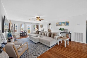 A spacious living room with a large sectional sofa, a wooden coffee table, and a patterned rug.