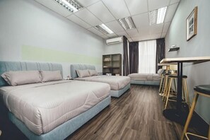 A hotel room with two beds, a sofa, a dining table, bar stools, and an air conditioning unit.