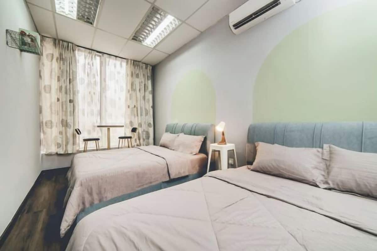 A hotel room with two beds, a desk, and a chair.