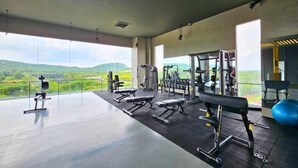 Un gimnasio espacioso con diversos equipos de ejercicio, amplias ventanas que ofrecen vistas al campo.