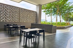 An outdoor seating area with tables and chairs, a decorative wall, and a view of greenery. - Bell Suite Cozy Home at Sunsuria City 16km to KLIA Sepang by Cloud Host (Sepang)