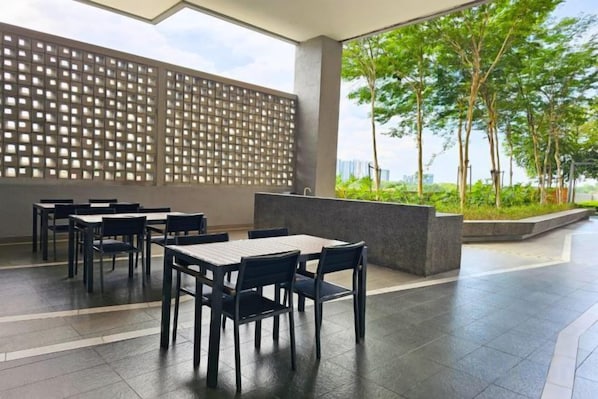 Un espace extérieur aménagé avec des tables et des chaises, un mur décoratif et une vue sur la verdure.